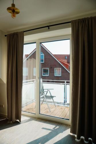 a sliding glass door with a view of a deck at Ferienwohnung KÖÖK Heimathafen - Modern, Balkon, Strandnah in Neuharlingersiel