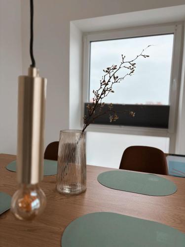 a wooden table with a glass vase and a window at Ferienwohnung KÖÖK Heimathafen - Modern, Balkon, Strandnah in Neuharlingersiel
