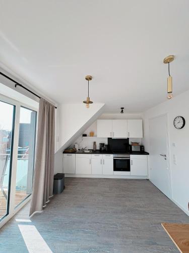 a kitchen with white cabinets and a large window at Ferienwohnung KÖÖK Heimathafen - Modern, Balkon, Strandnah in Neuharlingersiel