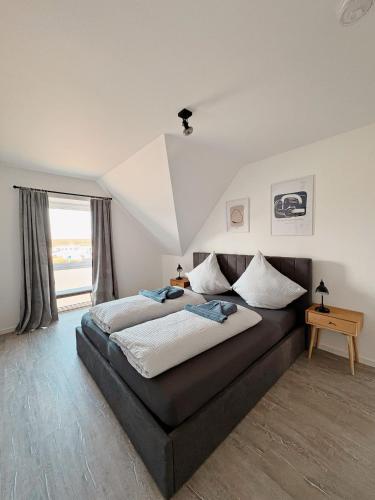 a bedroom with a large bed and a window at Ferienwohnung KÖÖK Heimathafen - Modern, Balkon, Strandnah in Neuharlingersiel