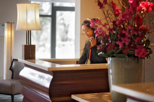 a woman standing in front of a counter with a vase of flowers at Tangla Hotel Brussels in Brussels