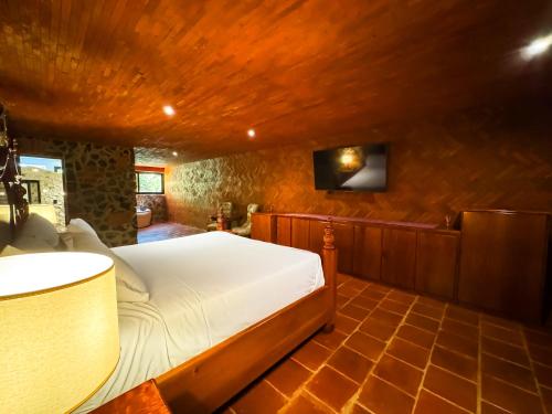 a bedroom with a bed and a tv on a wall at Le Suisse Spa in Santa Lucía Milpas Altas