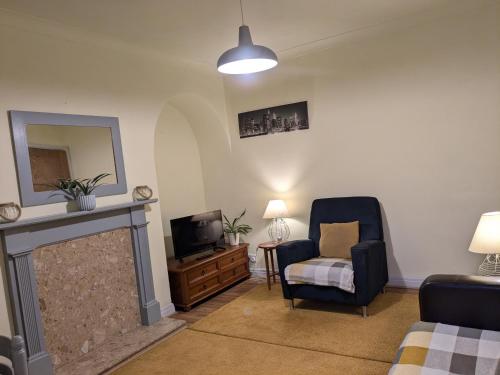 a living room with a fireplace and a chair and a television at Apartment with Outside Patio and Car Space in Durham