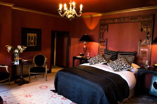 a bedroom with a large bed with red walls at The Fox and Hounds in Oakham