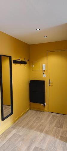 a room with a tv and a yellow wall at Votre Refuge Urbain Logement Complet pour Étudiants et Pros in Fougères