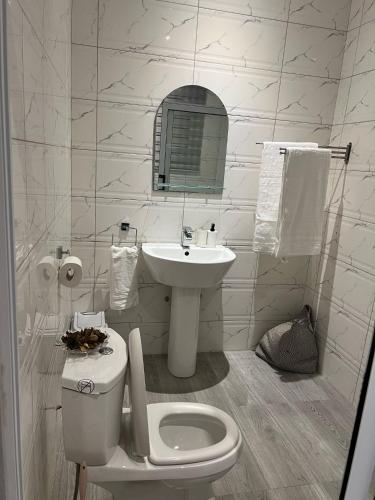 a white bathroom with a toilet and a sink at Vickkesnat Luxury Homes in Kasoa