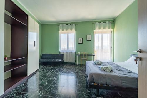 a bedroom with green walls and a bed and a couch at Casa Lungogesso in Cuneo