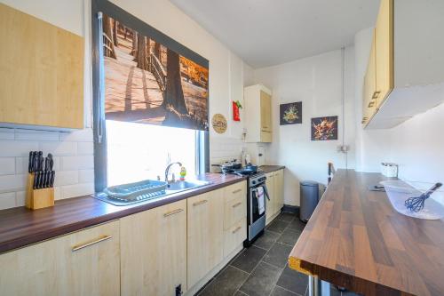 a kitchen with wooden cabinets and a sink and a window at -RA27A- For your relaxed, Cosy stay, Free Parking in Leeds