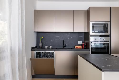 a kitchen with white cabinets and a black counter top at Family Joy - Close to city centre in Lugano