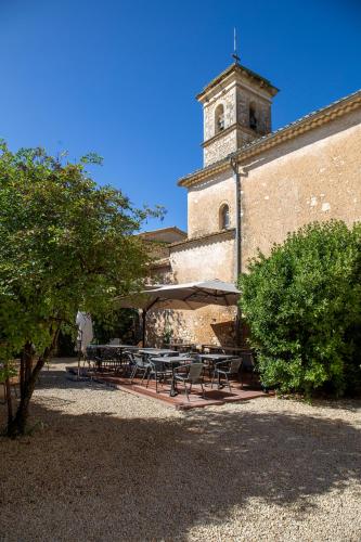 un groupe de tables et de parasols devant un bâtiment dans l'établissement L’auberge de Montsalier, à Le Plan
