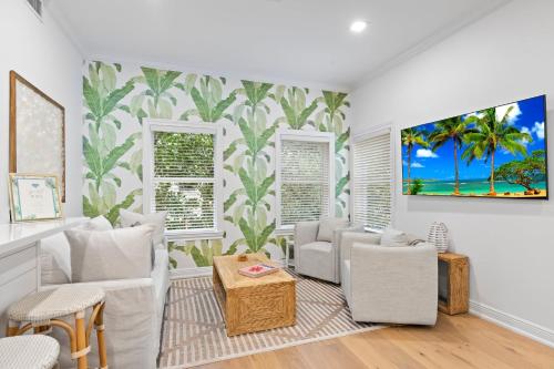 a living room with white furniture and a tropical wallpaper at The Palm Beach House - Tropical in Palm Beach