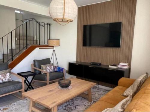 Una sala de estar con un sofá y un televisor en una pared. en Modern Executive Stay, en Upington