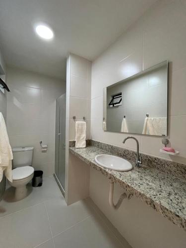 a bathroom with a sink and a toilet and a mirror at Itacimirim Beach Unique in Camacari