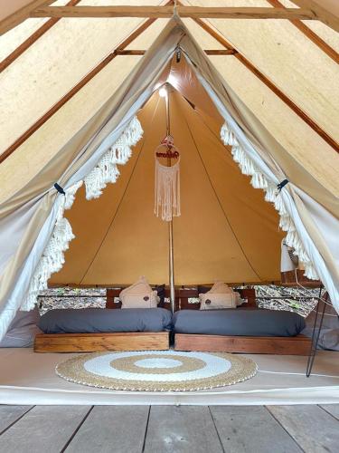 a tent with a bed and a rug in it at Lainkalogos Glamping in Rabia