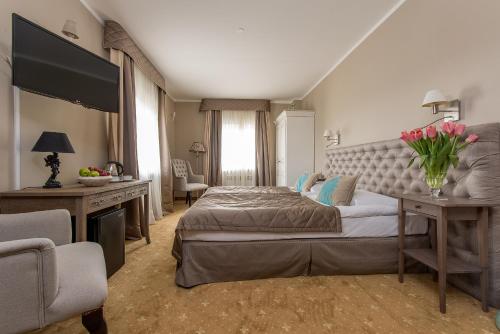 a bedroom with a bed and a desk with flowers on it at Riviera Resort Airport Modlin in Olszewnica Nowa