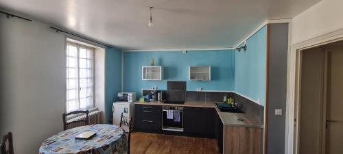 d'une cuisine avec des murs bleus, un évier et une table. dans l'établissement Saint Eloi habitat, à Crocq
