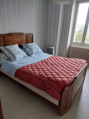 - un lit avec une couette et des oreillers rouges dans une chambre dans l'établissement Saint Eloi habitat, à Crocq