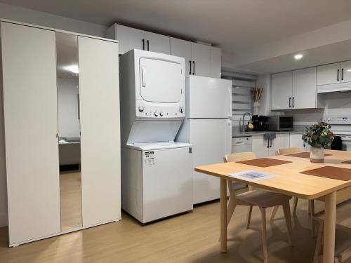 a kitchen with white cabinets and a table and a refrigerator at Levida Living - Cozy 2 Bedroom Suite at the Heart of Langley in Langley