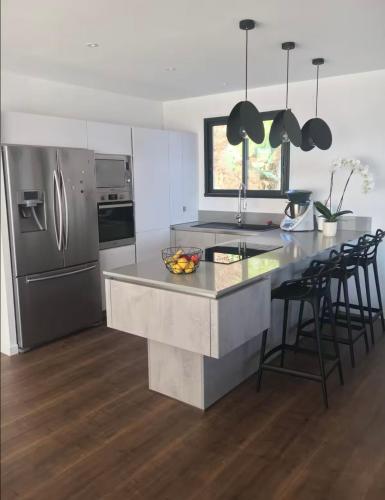 une cuisine avec des appareils en acier inoxydable et un comptoir avec des chaises dans l'établissement Haut de villa avec piscine au bord de mer, à San-Martino-di-Lota