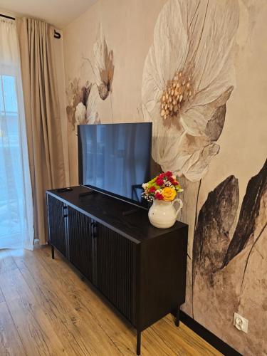 a living room with a television and a vase with flowers at F&R Sea Bliss Apartment in Gdańsk