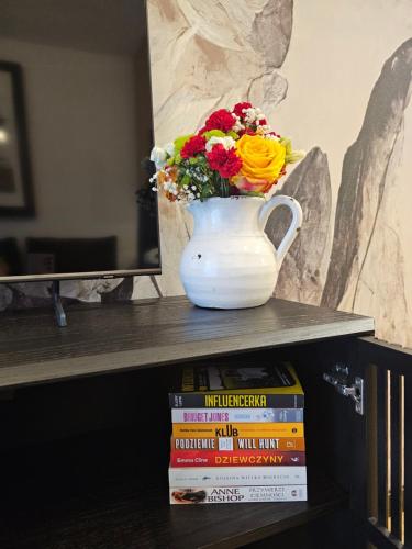 a vase filled with flowers sitting on top of books at F&R Sea Bliss Apartment in Gdańsk
