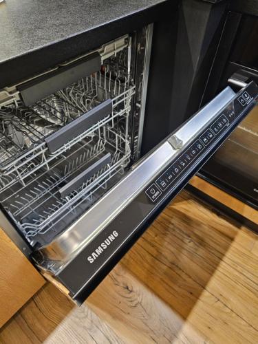 a dishwasher with its door open on a wooden floor at F&R Sea Bliss Apartment in Gdańsk