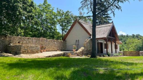 a small house with a stone wall and a yard at Thatched cottage in Dörgicse