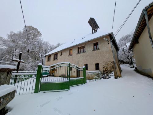 a house with a green fence in the snow at L'École Buissonnière - Embrun in Embrun
