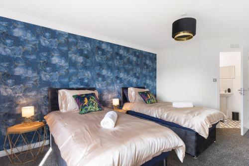 two beds in a room with a blue wall at Deluxe 2-Bedroom Serviced Apartment near Windsor Castle & M4 - Free Parking in Windsor