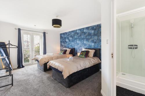 a bedroom with two beds and a blue wall at Deluxe 2-Bedroom Serviced Apartment near Windsor Castle & M4 - Free Parking in Windsor