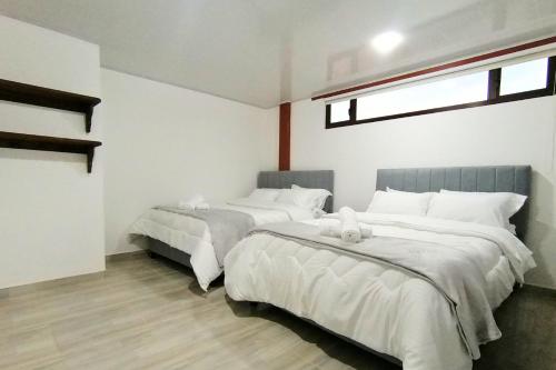 a bedroom with two beds with white sheets and a window at Apto 205 Apartahotel Los Pinos in Sáchica