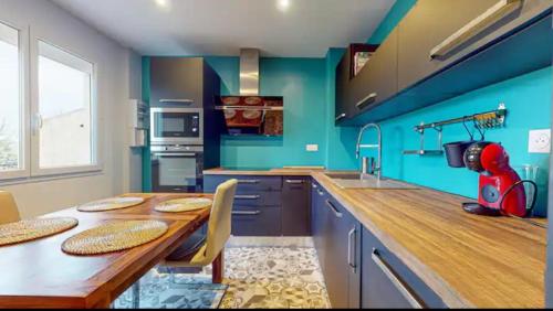 a kitchen with a wooden table and blue walls at Light T 3 air conditioning Two balconies Toulouse in Toulouse