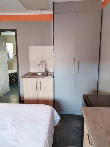a small kitchen with a bed and a sink at Reutlwane Gardens B&B in Secunda