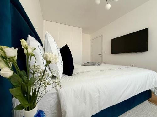 a bedroom with a white bed with a tv on the wall at MK Luxury Stay in Skopje