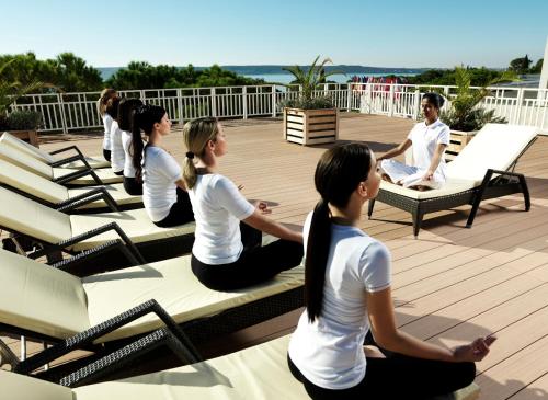 a group of people sitting on a bench doing yoga at Wellness Hotel Apollo – Terme & Wellness LifeClass in Portorož