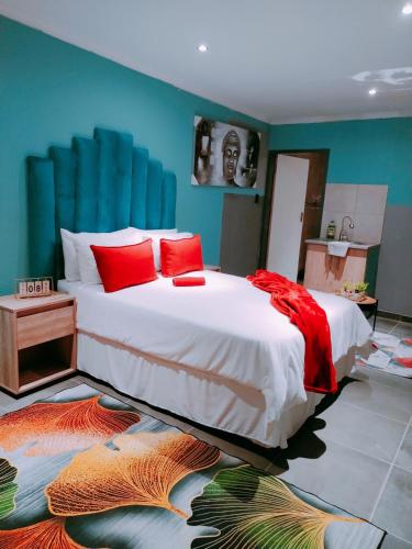 a bedroom with a large bed with red pillows at Reutlwane Gardens B&B in Secunda