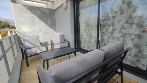 un soggiorno con divano e una sedia sul balcone di Appartement proche de La Rochelle centre ad Aytré