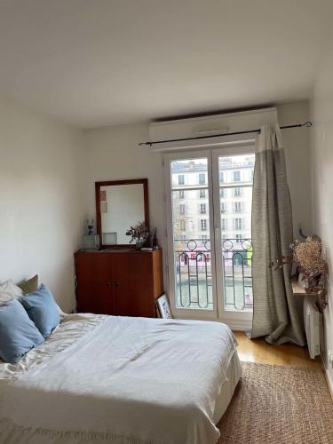 une chambre avec un lit et une grande fenêtre dans l'établissement Spacious and bright apartment - Canal St-Martin, à Paris