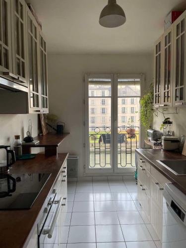 une cuisine avec des placards blancs et une grande fenêtre dans l'établissement Spacious and bright apartment - Canal St-Martin, à Paris