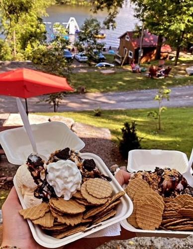 a person holding two plates of food on a table at Off Grid Wildwood Bunkies in Bailieboro