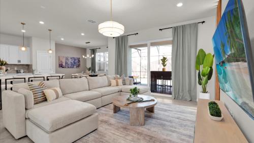 a living room with a white couch and a kitchen at Family Home w Cinema, Pool & BBQ Clermont in Orlando