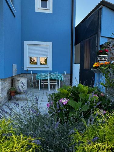 a blue house with a table and a window at Apartman Nonno Božo 1 in Fažana