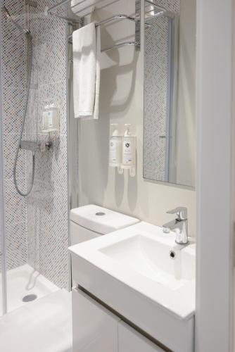 a white bathroom with a sink and a shower at M'AR De AR Auria in Lisbon