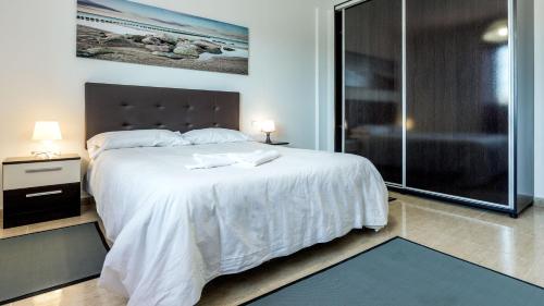 タラハレホにあるTarajalejo Villageのベッドルーム(大きな白いベッド1台、ガラス張りのシャワー付)