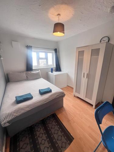 a bedroom with a bed with two blue towels on it at Colebert Avenue in London