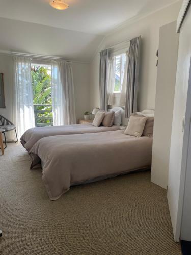 a large bed in a bedroom with two windows at Bavaria Boutique Hotel in Auckland