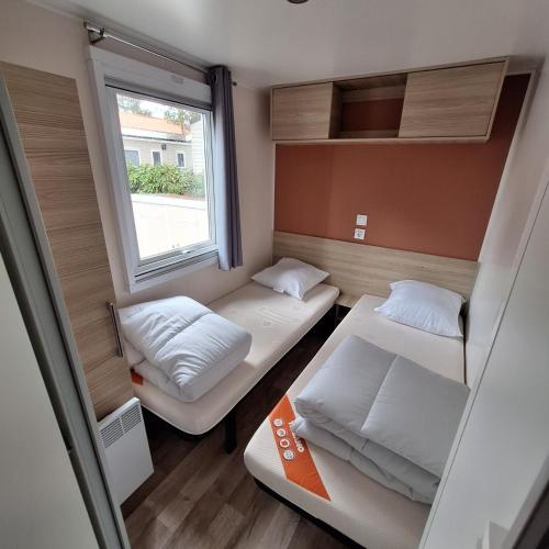 une petite chambre avec deux lits et une fenêtre dans l'établissement mobil-home family 6-8 personnes Camping 4 étoiles bois dormant, à Saint-Jean-de-Monts