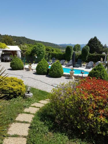 un jardin avec une piscine et quelques buissons dans l'établissement Charmant 2 pièces tout confort, à Régusse