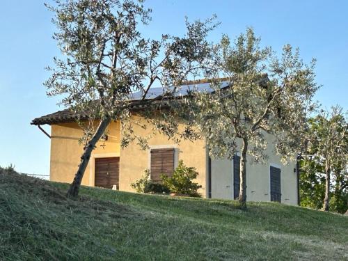 a house on top of a hill with two trees at Agriturismo Colle Bello in Spoleto