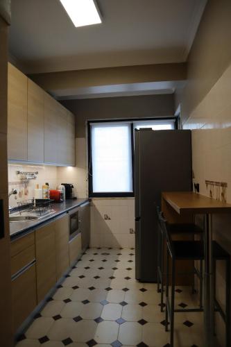a kitchen with a black refrigerator and a table at Apartamento Moderno e Acolhedor I Perto do Aeroporto in Lisbon
